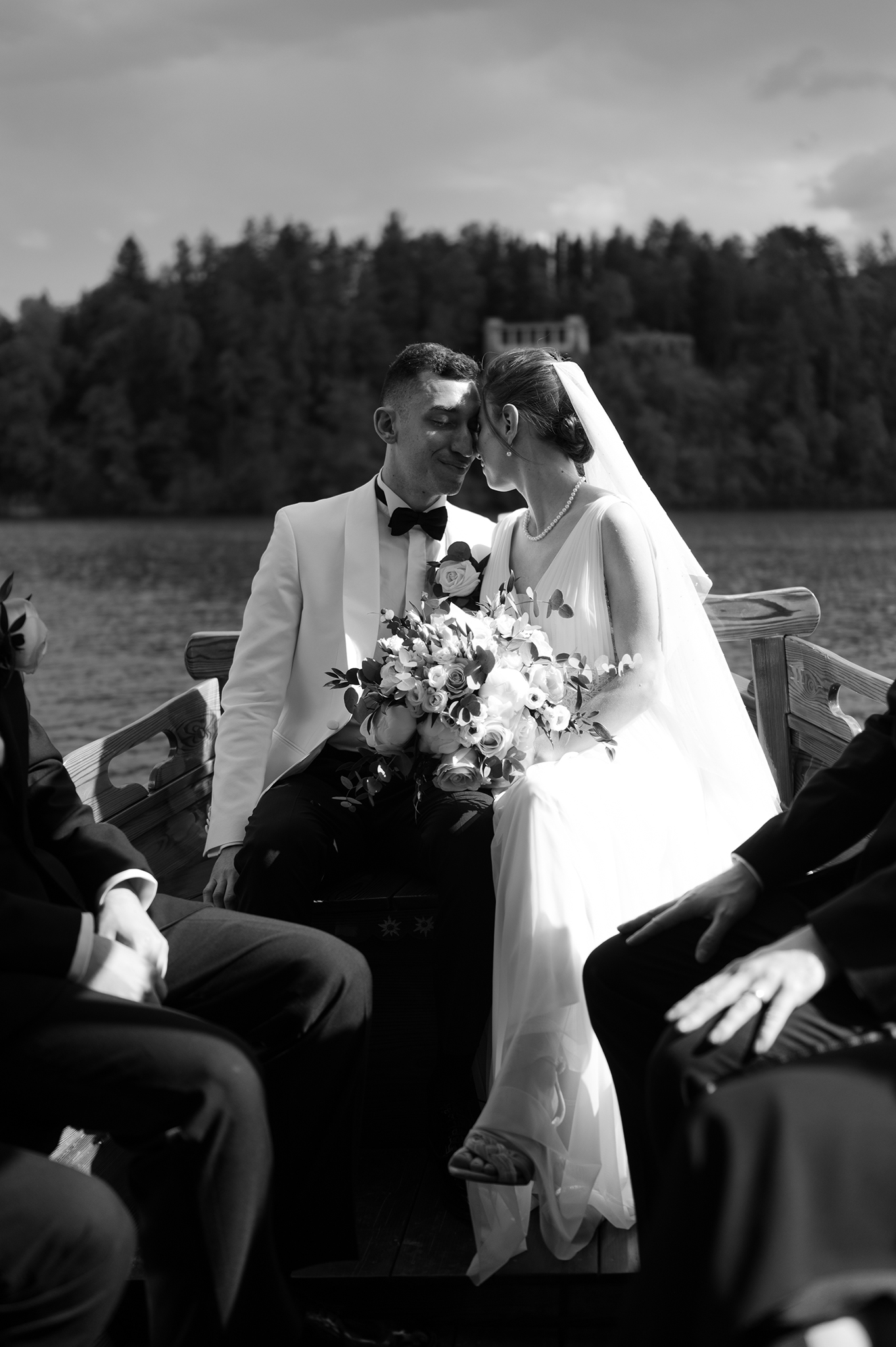 Bride and groom resting their heads while sitting on a pletna boat on Lake Bled