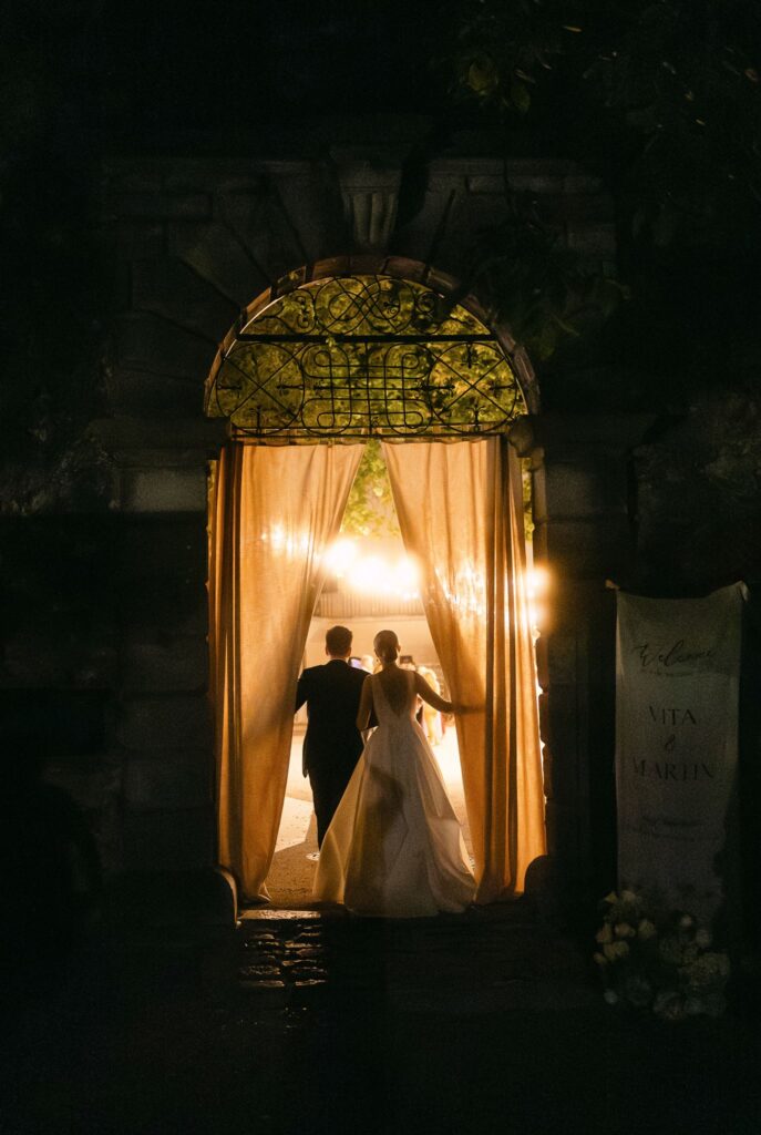 Wedding couple walking through fabric to their candle lit reception