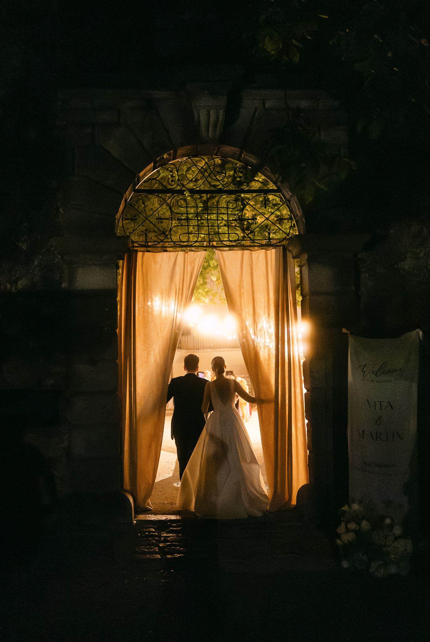 Wedding couple walking through fabric to their candle lit reception